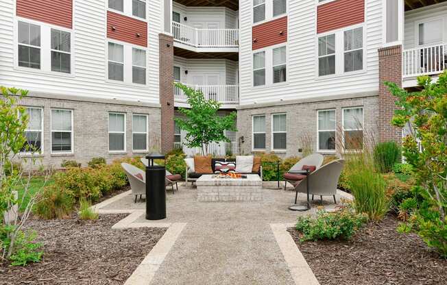 A courtyard with a black trash can and a bench with a cushion on it.