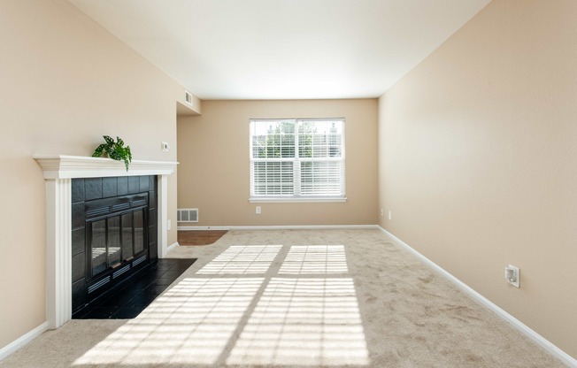 an empty living room with a fireplace and a window