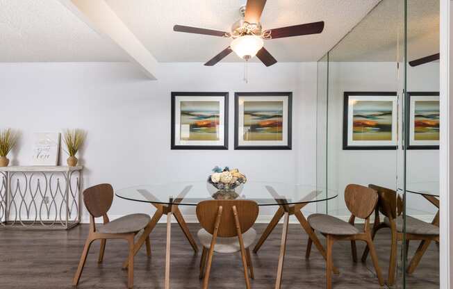 a dining room with a glass table and chairs and a ceiling fan