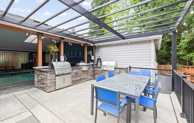 A patio with a table and chairs and a grill.