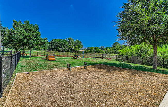 a fenced in dog park with trees and a bench at Discovery at Craig Ranch, Texas, 75070