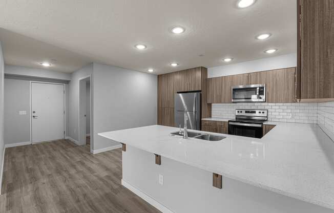 an empty kitchen with a white counter top and a stainless steel stove and refrigerator