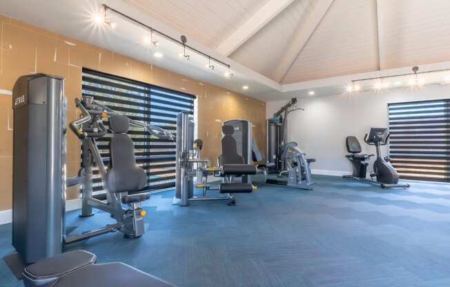 a gym with weights and cardio equipment in a building with white walls