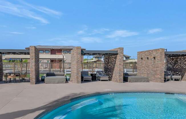 A pool surrounded by stone pillars and a building in the background.