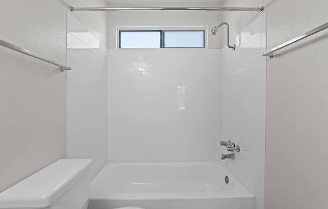 A white bathroom with a tub, toilet, and sink.