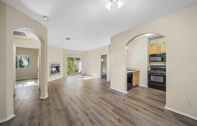 a living room and kitchen with hardwood floors and a fireplace at The Village Apartments, California