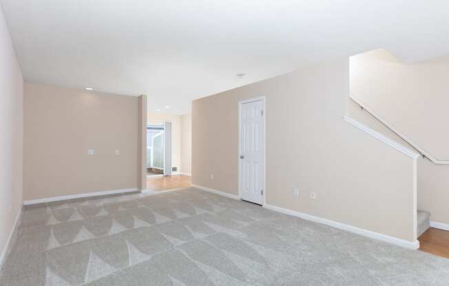 an empty living room with a staircase and a white door