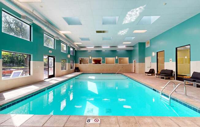 A large indoor swimming pool with a sunny view outside.