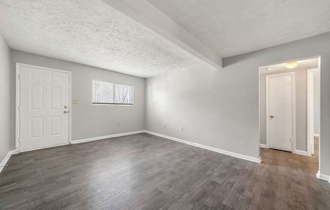 the living room and dining room of an apartment with white walls and wood floors