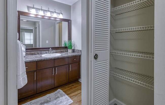 A bathroom with a large mirror, sink, and wooden cabinets.