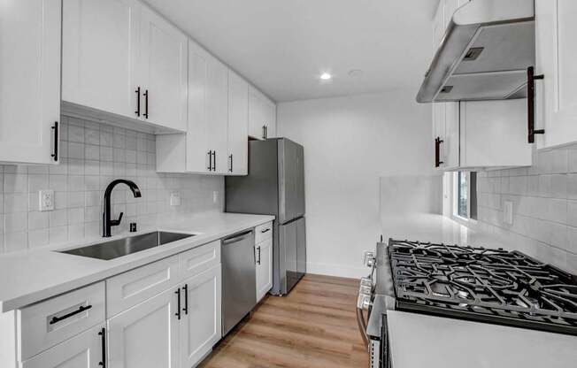 a white kitchen with white cabinets and stainless steel appliances