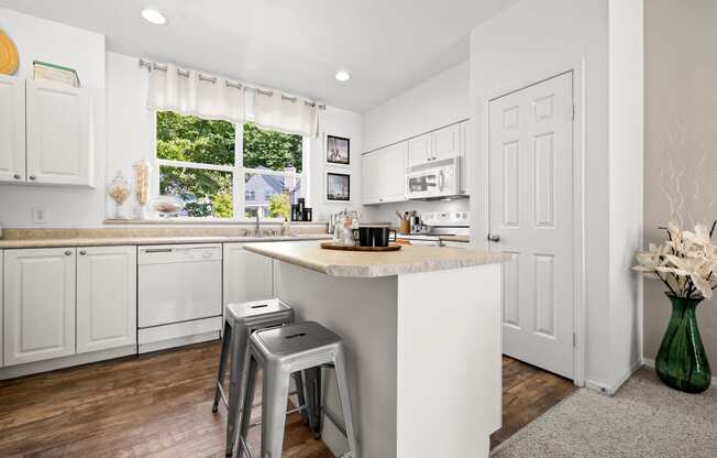 a kitchen with white cabinets and a white island with two stools