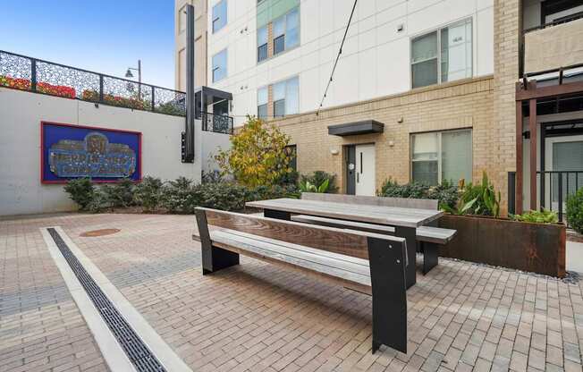 A bench is situated on a brick patio in front of a building.