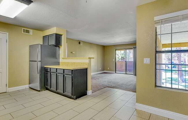 an empty kitchen and living room with a refrigerator