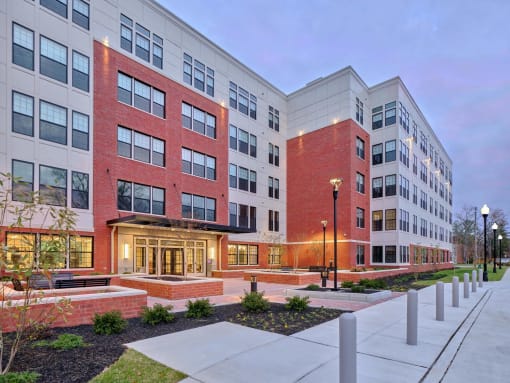 an exterior view of an apartment building at dusk at The Encore at Ingram Manor, Pikesville, MD, 21208