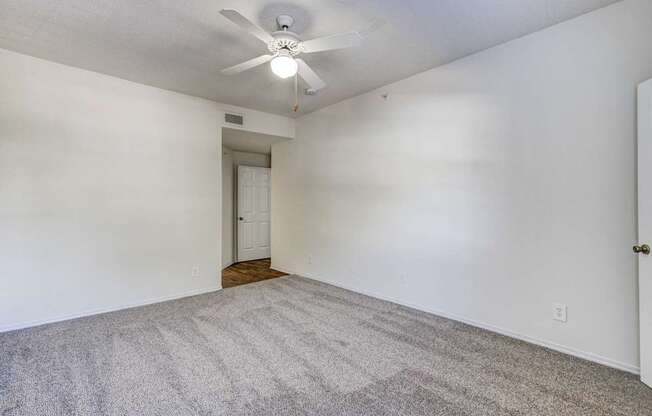Large primary bedroom at Saxony at Chase Oaks Apartments in Dallas, TX, featuring a ceiling fan, walk-in closet, and natural light through large windows.