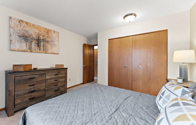 A bedroom with a bed, dresser, and painting on the wall.