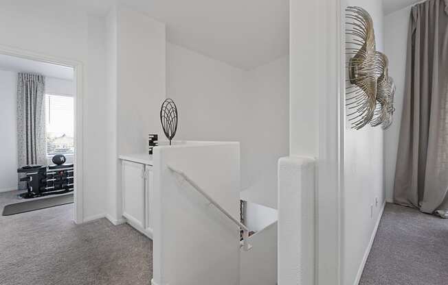 a living room with white walls and a white staircase and a room with a window