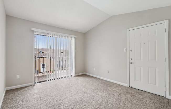 A room with a white door and a window with a view of a building outside.