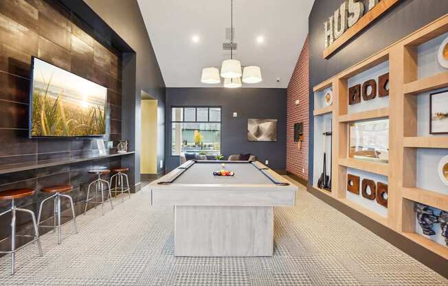 a pool table in a room with a bar and a tv