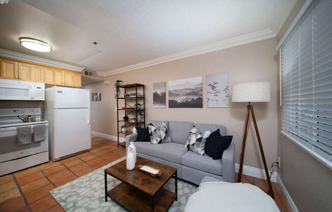 Living room with large window and open kitchen in model unit at the Atrium Apartments in San Diego, California.