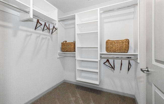 a walk in closet with white shelves and a white closet door