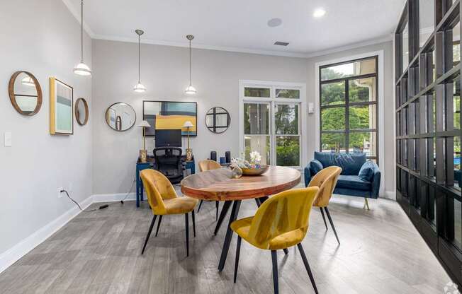 A modern dining room with a round table and yellow chairs.