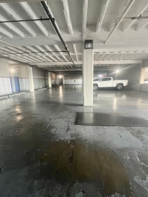 A white truck is parked in a large, empty parking garage.