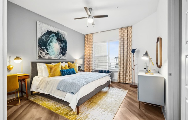 A bedroom with a bed, a desk, and a ceiling fan.