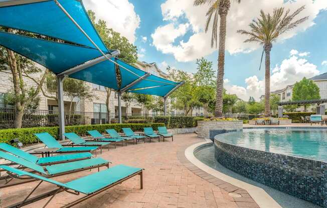 A pool area with sun loungers and a blue canopy.