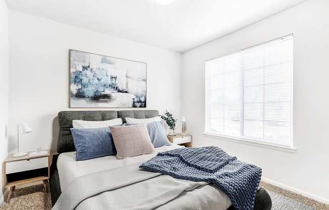 Model Bedroom with Bed Under Wall Art, Nightstand Next to Large Window