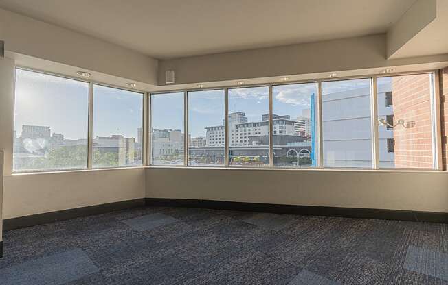 an empty living room with large windows and a city view