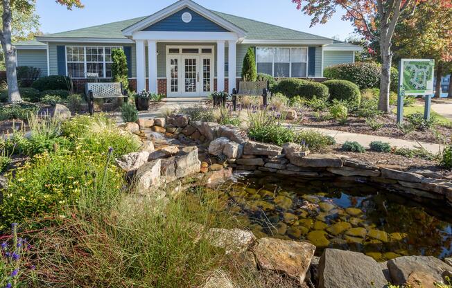 Building exterior with a pond and garden at Ashley Oaks Apartments in Greensboro, North Carolina