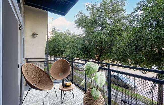 a balcony with two chairs and a tree