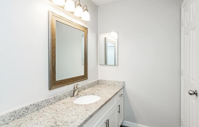 a bedroom area with a sink and a mirror