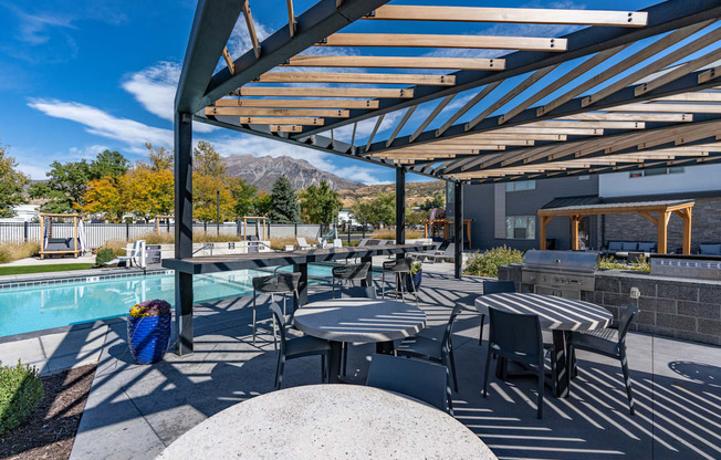 a patio with tables and chairs next to a pool