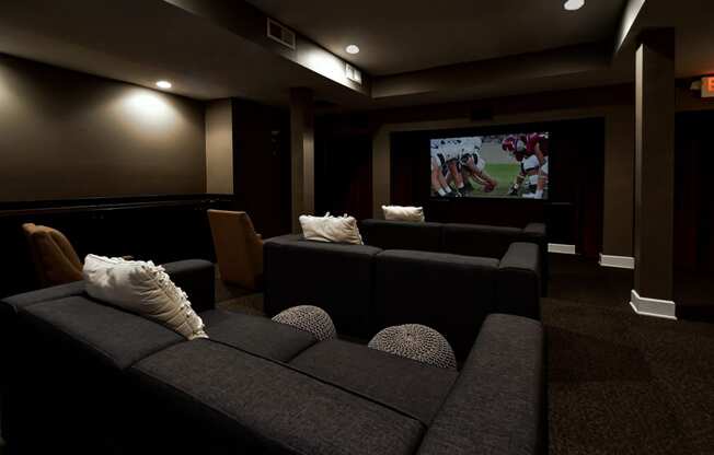 a home cinema room with black furniture and a flat screen tv