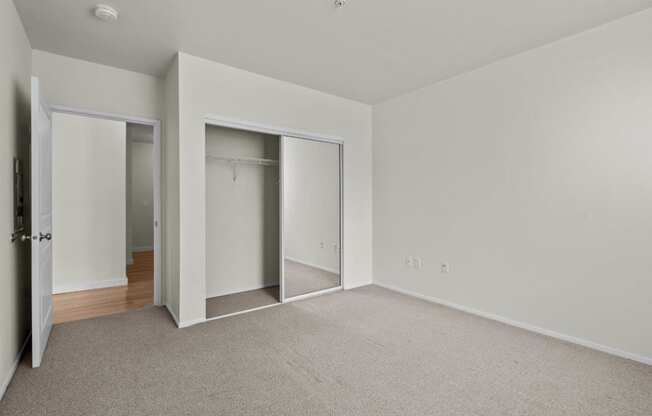 an empty bedroom with closet doors and carpet