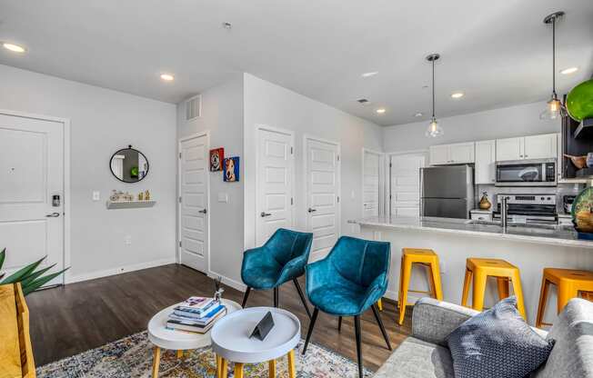 a living room with a kitchen with a bar and stools