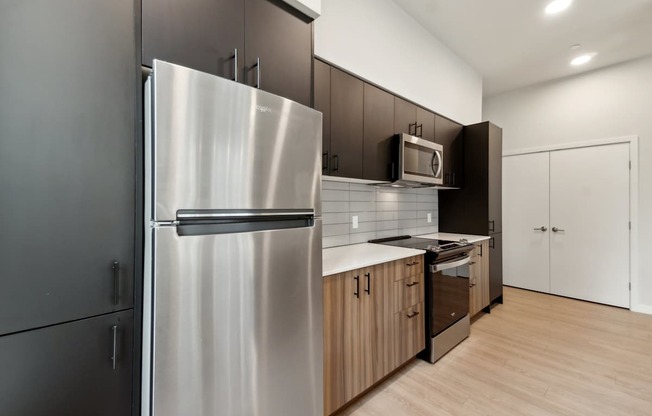 A modern kitchen with a stainless steel refrigerator and wooden cabinets.