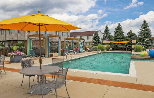 our apartments have a swimming pool and patio with chairs and umbrellas at Village Club of Rochester Hills, Shelby Township, MI