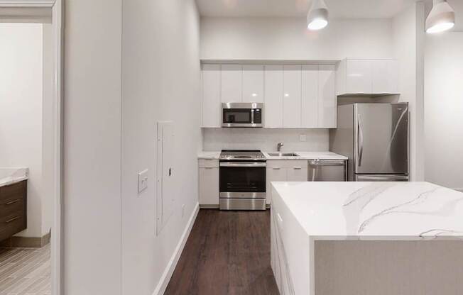 A kitchen with a white counter top and stainless steel appliances.