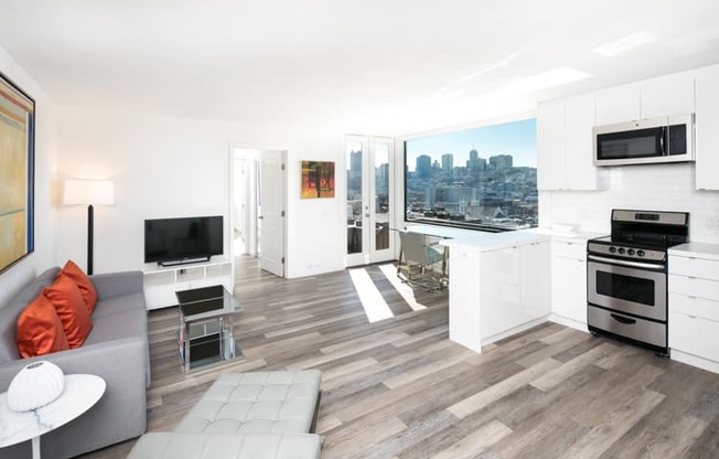 an open living room and kitchen with a large window and a view of the city