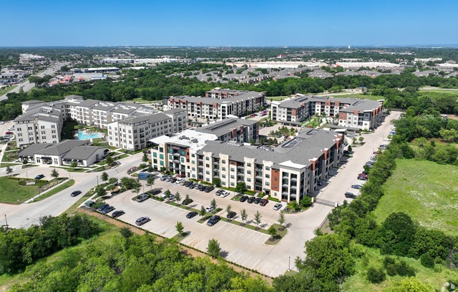 A bird's eye view of a large apartment complex surrounded by greenery and roads. at Aurora Watson Branch, Texas