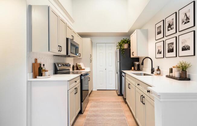 The light finish kitchen package features white shaker-style cabinetry, quartz countertops, stainless steel appliances, and a geometric tile backsplash that creates a bright, modern aesthetic.