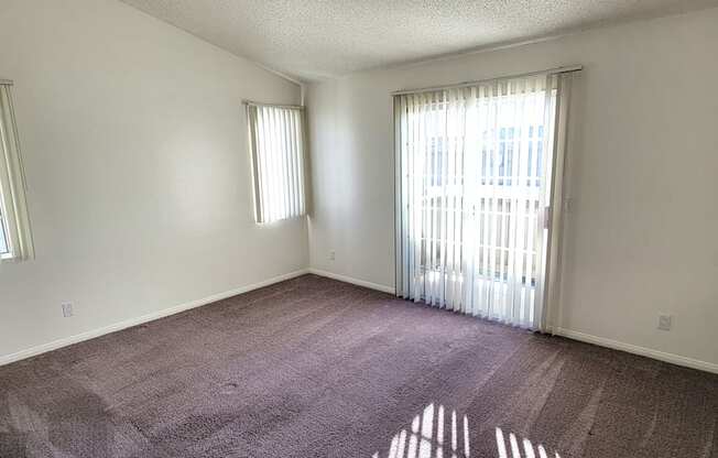 Large carpeted bedroom with private porch and lots of natural light at Northwoods Apartments in Upland, California.