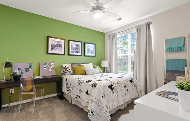 a bedroom with green walls and a white desk with a computer