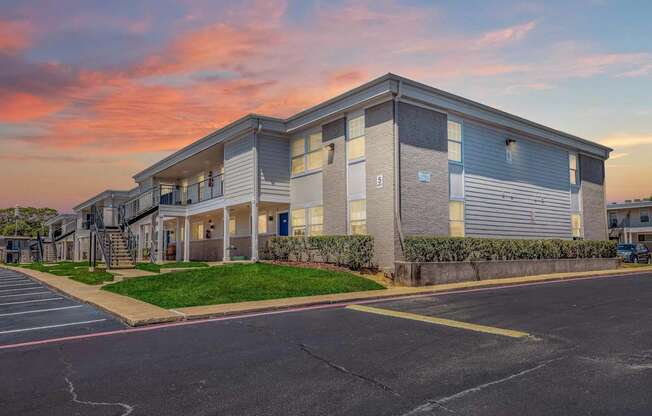A modern apartment building with a parking lot in front.