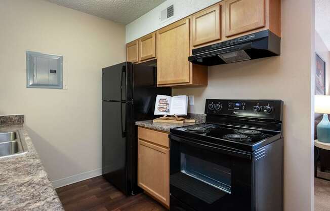 a kitchen with black appliances and wooden cabinets and a black refrigerator