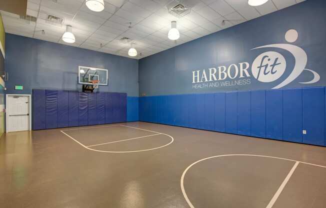 a basketball court in a room with a blue wall and a scoreboard
